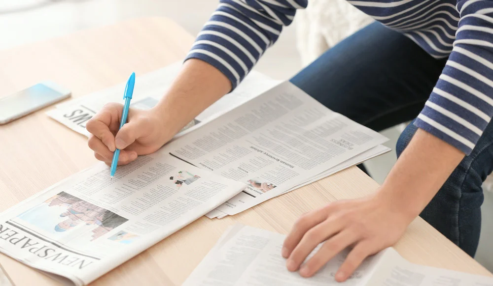 Young man searching classifieds in newspaper at home