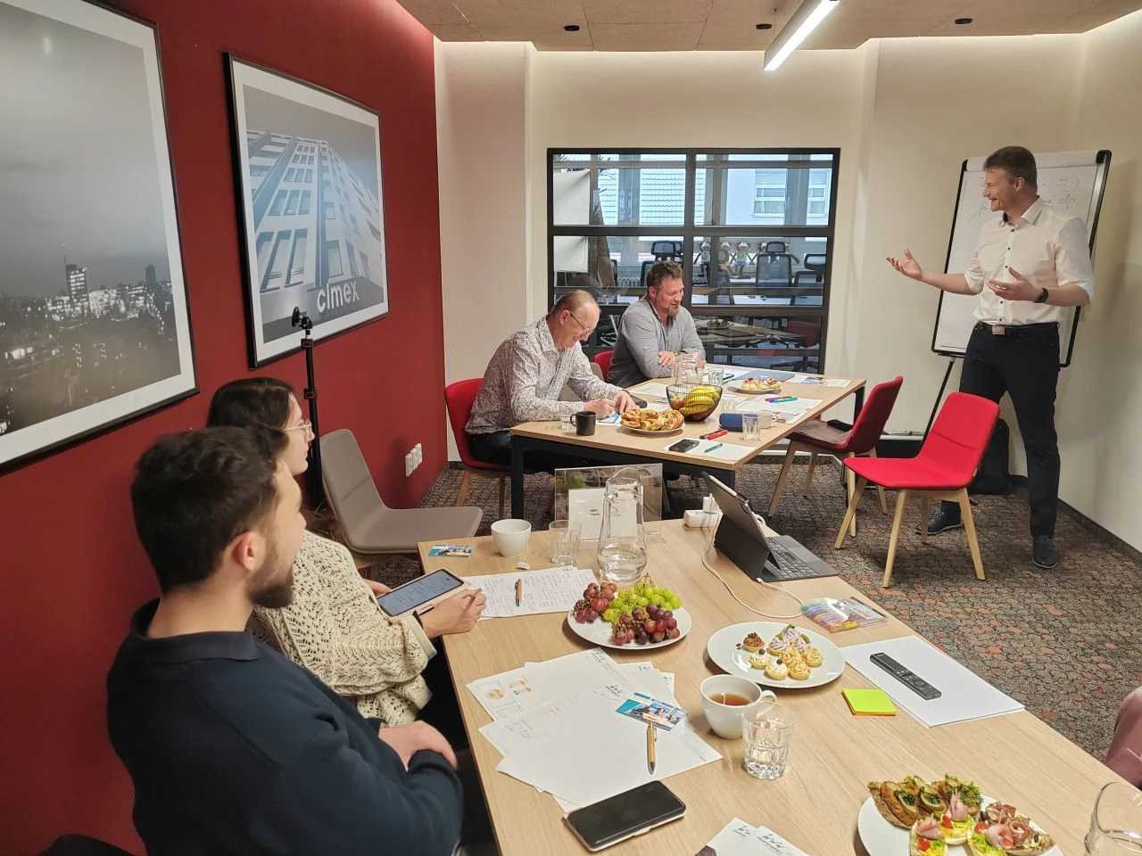 Dvě skupiny účastníků diskutují s lektorem během workshopu, znázorňuje praktické vzdělávání zaměřené na komunikaci a spolupráci.